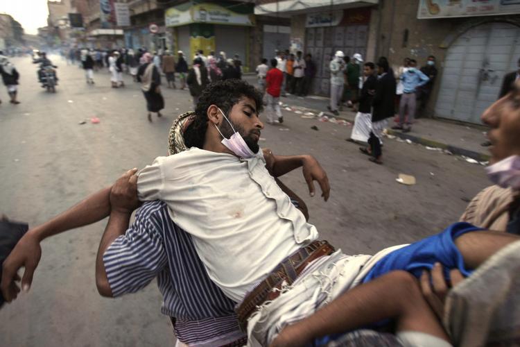 Protester. Hele ugen har været blodig i Yemen. Her bæres en såret aktivist væk fra regerings skyderier søndag. 