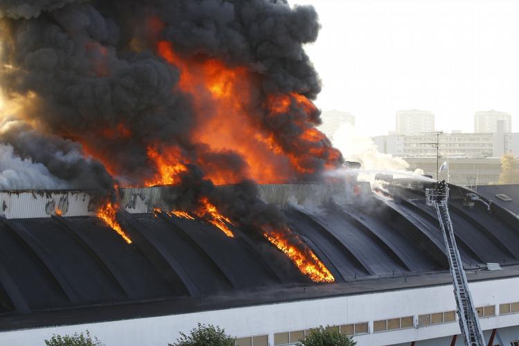 flammer. Ilden har fat i tagkonstruktionen, og der lyder høje knald inde fra KH-Hallen 