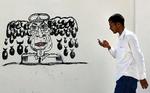 Satire. Tripoli i går. En mand passerer en graffiti med Libyens afsatte diktator, Moamar Gaddafi, som gemmer sig et eller andet sted. 