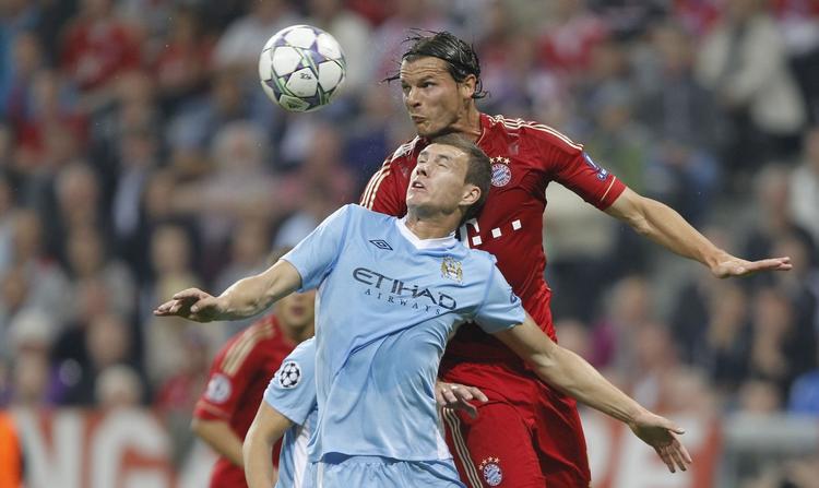 Både spillere fra Bayern München og Manchester City nyder godt af de mange tv-penge, der er i henholdsvis Premier League og Bundesligaen. Der er Daniel van Buyten (bagerst) i nærkamp med City-spilleren Edin Dzeko i et opgør i den paneuropæiske Champions League-turnering. 