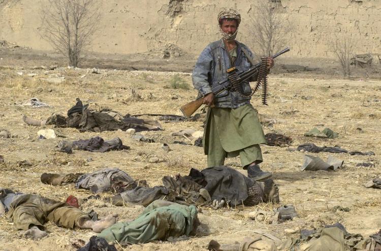2001: Krigen i Afghanistan er gået igang. På billedet ses en soldat fra Den Nordlige Alliance blandt dræbte Taleban-soldater. 