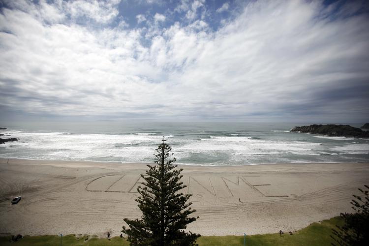 FORURENING. En desperat newzealænder har skrevet 'Rens mig' i sandet på Maunganui-stranden, der trues af udslippene fra det strandede containerskib 'Rena'. 