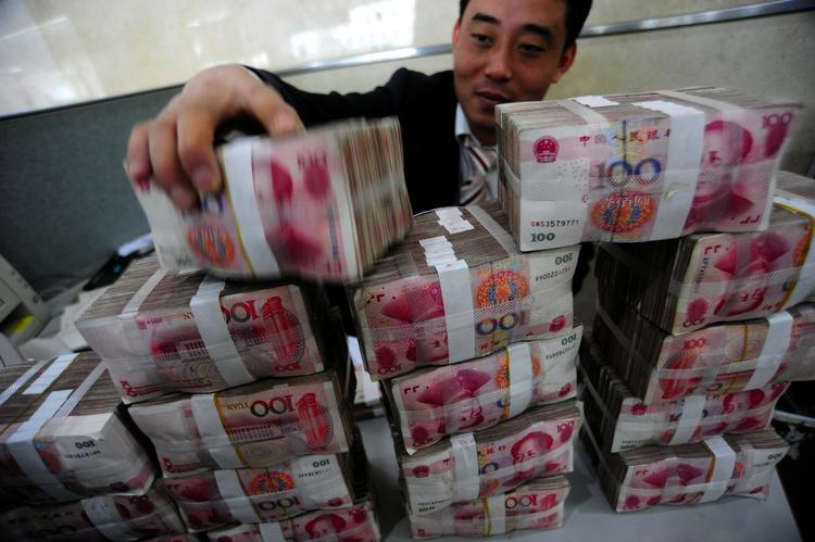 magt. En kinesisk bankansat stabler bundtvis af den kinesiske valuta, Yuan. 