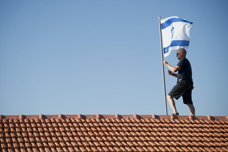 Gilad Shalits far, Noam, rejser det israelske flag på toppen af sit hus i Mitzpe Hila i det nordlige Israel. Snart kan han se frem til at blive genforenet med sin søn, der har været taget til fange af Hamas siden 2006. 