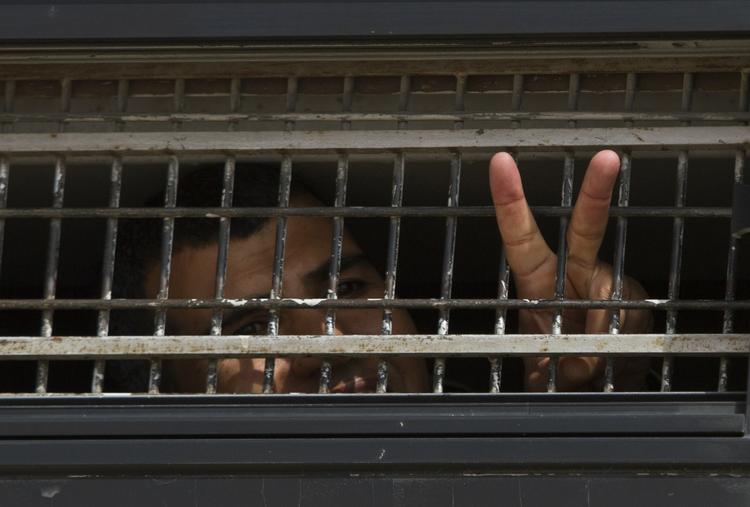 fri. En palæstinensisk fange viser sejrstegn gennem tremmerne på en af de busser, der i øjeblikket fragter de 477 fanger, der skal frigives i første omgang. Fangerne samles på to institutioner inden frigivelsen, der ventes at finde sted i denne uge. 