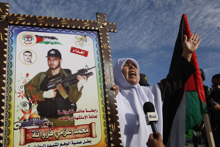 velkomst. En del af de frigivne palæstinensiske fanger ankommer til grænsebyen Rafah, hvor en kvinde holder på et portræt af en dræbt militant fra den islamistiske bevægelse Hamas. 