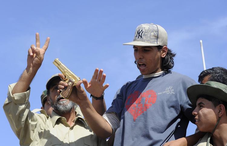 guldpistol. Den unge oprørssoldat MOhamed El Bibi fremviser den guldbelagte pistol, som han siger, han tog fra gaddafi, da han belv fundet i et betonrør i Sirte. 