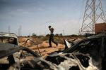 En libysk soldat går forbi de udbrændte rester af Moamar Gaddafis konvoj. Den tidligere libyske diktator blev dræbt efter, at han blev taget til fange i torsdags. 