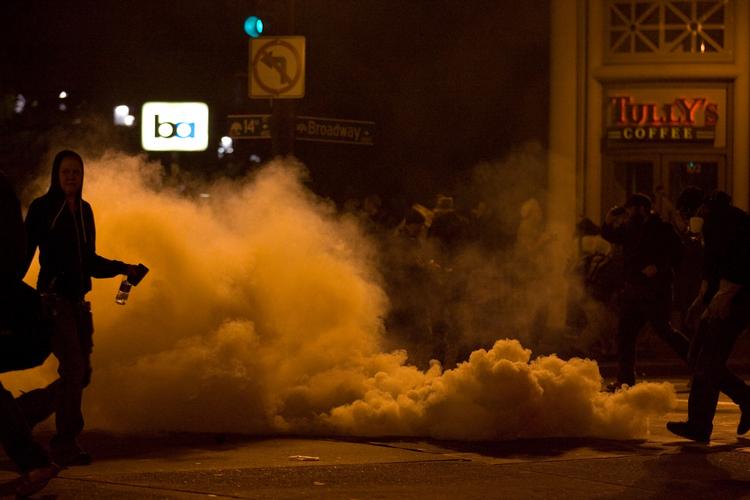 RYDNING. Tåregas og demonstrant fotograferet under sammenstøddene i Oakland i Californien. 