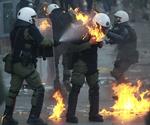 optøjer. En gruppe betjente forsøger at slukke ilden fra en benzinbombe under en demonstration i det centrale Athen 20. oktober. 
