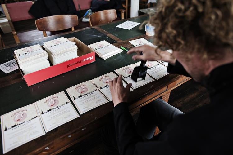 folkeaktie. Christianitter vil introducere sociale aktier som Christiania folkeaktier på Wall Street. Her ses frivillige, der sætter serienumre på aktierne i forbindelse med lanceringen af aktierne tidligere i år. 