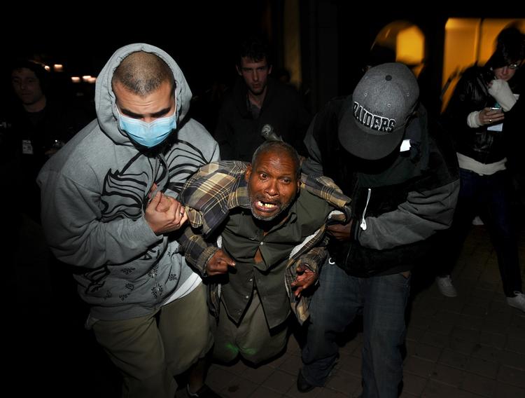 En Occupy Oakland demonstrant, såret af skud fra politiet, hjælpes væk af andre demonstranter. 