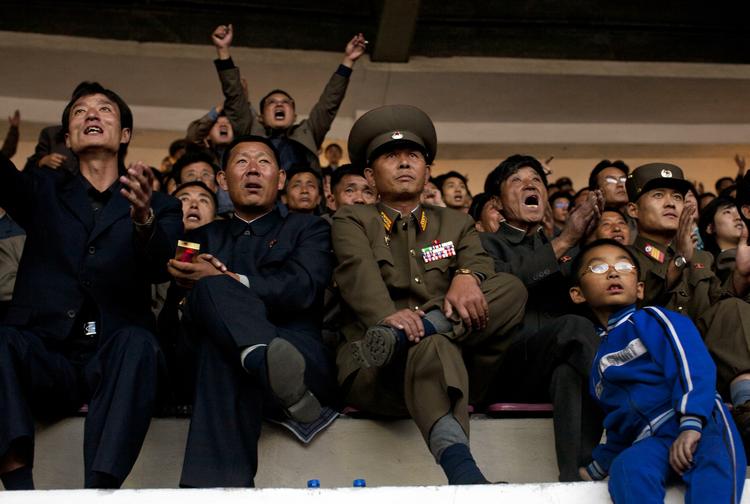 Nord-Koreanske fodboldfans hepper på deres landshold under en kamp mod Uzbekistan på Yanggakdo Stadium i Pyongyang. 