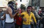 Kamp. Demonstrerende på Tahrir-pladsen i Kairo hjælper en såret mand. Kampene sker kun 9 dage før de første demokratiske valg i landet siden Hosni Mubarak gik af som præsident. 