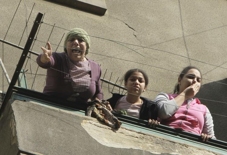 En kvinde skriger på hjælp, mens en nabobygning står i flammer. 