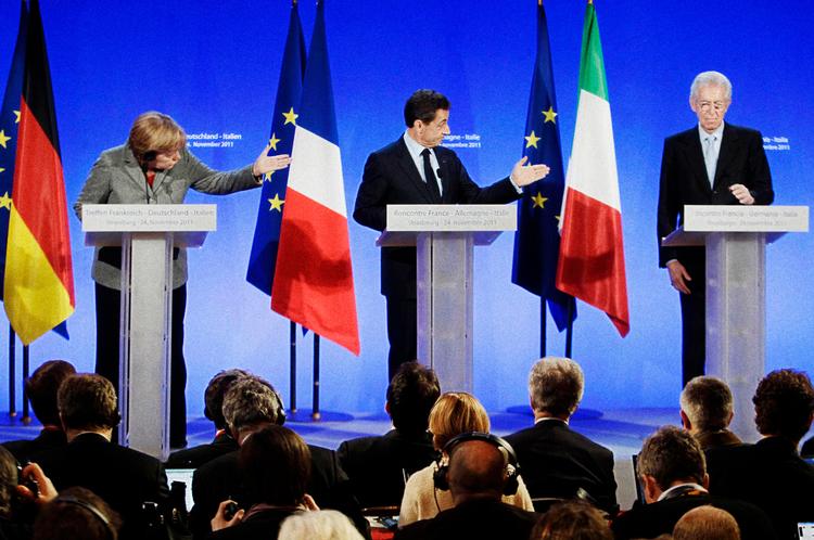Krisesnak. Pilen har peget mod Italien - her personificeret ved den nye ministerpræsident, Mario Monti (th.) - når eurokrisen har været til debat. Nu må også Tyskland og Merkel (tv.) vænne sig til at stå for skud. 