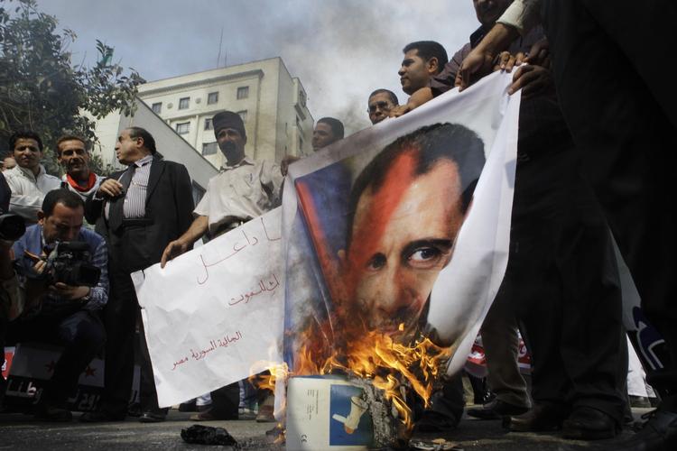 Syriske demonstranter brænder et billede af præsident Bashar Assad under en demonstration foran Den Arabiske Ligas hovedkvarter i den egyptiske hovedstad Kairo. 