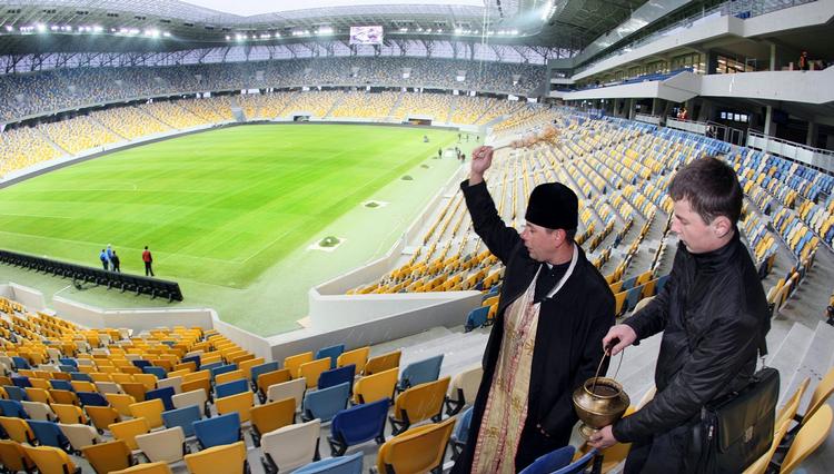 klar? En præst velsigner et nyåbnet stadion i Lviv i Ukraine i november. Lviv bliver en af de fire EM-byer i Ukraine. 