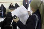 PARLAMENTSVALG. Vælger nærstuderer stemmesedlen foran de valgtilforordnede i et valglokale i Giza. 