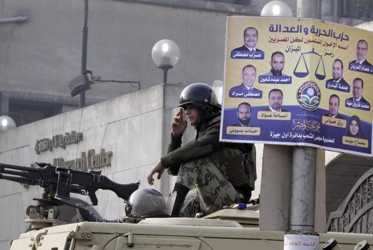 afventende. Kairo i dag. En egyptisk soldat på vagt foran en plakat med kandidater for Det Muslimske Broderskab. 