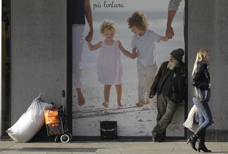 Forbipasserende. En kvinde passerer en tigger i den italienske by Milano. 