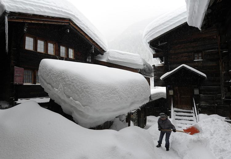 Sne, sne og sne. En person skovler sne i Blatten i Schweiz. Nogle steder i landet ligger der op til to meter sne. 