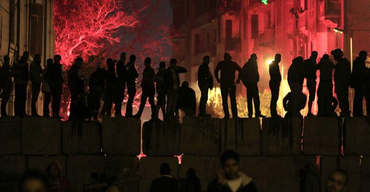 vrede. Demonstranter står på en cementblok, som adskiller det forhadte indenrigsministerium fra Tahrir-Pladsen. 