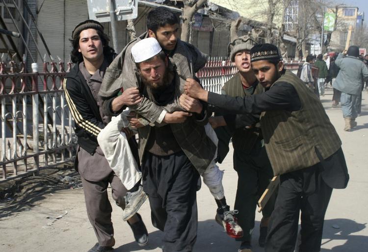 uroligheder. Afghanere bærer en såret mand under en anti-amerikansk demonstration i Kunduz nord for hovedstaden Kabul i går. 