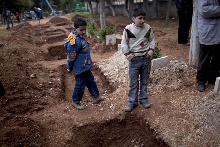 begravelse. Et par drenge deltog i går i begravelsen af tre syriske oprørssoldater i byen Idlib i den nordlige del af landet. 