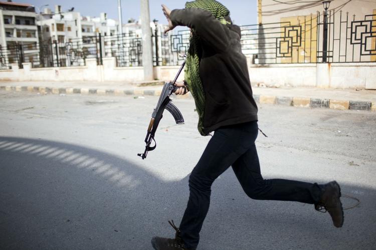 Dialog? I den nordlige by Idlib i Syrien fortsatte kampene i går, mens præsident Assad holdt møde med den tidligere FN-chef Kofi Annan. Her forsøger en syrisk oprører at flygte i dækning under angreb fra Assads tropper. 