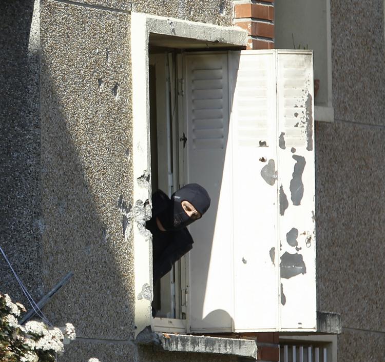 POLITI. Efterforskere har ledt efter spor efter at Merah var bestilt til at udføre angrebene på franske soldater og skolebørn. Her stikker en person fra specialstyrken hovedet ud af det vindue, som Merah havde barrikaderet sig bagved. 