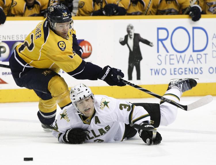 snublet. Dallas Stars' Stephane Robidas må en tur i isen i en kamp om pucken med Mike Fisher fra Nashville Predators. 