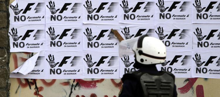 sammenstød. En politimand i Bahrain står foran en væg med protestplakater mod Formel 1-løbet i oliestaten. 