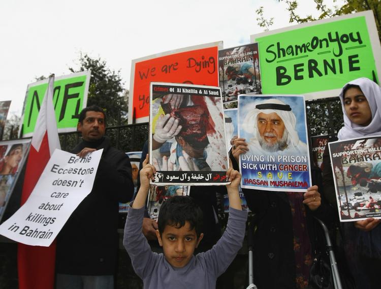 protest. 'Skam dig Bernie' står der på plakaten til højre. Kvinden hentyder til lederen af Formel 1-cirkusset, Bernie Ecclestone, der har instisteret på at afvikle dagens løb i Bahrain. 