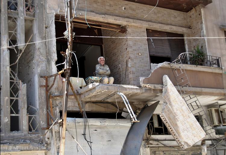 ØDELÆGGELSER. Syrer på balkonen i sit kraftigt beskadigede hus efter et af regimets bombardementer i Homs. 