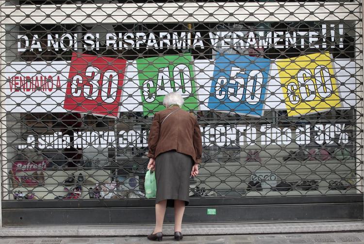 Ironisk. 'Her kan du virkelig spare penge', står der' ironisk i et butiksvindue i en lukket italiensk forretning. 