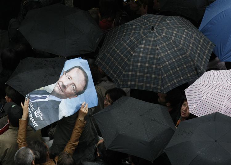 BESKYTTELSE. En valgplakal for Francois Hollande bruges som ly mod regnen under valgmøde i Tulle i Midtfrankrig søndag. 