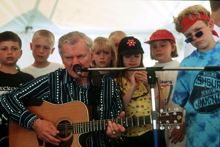 Bluegrass. Doc Watson på scenen med unger til 'MerleFest' i Wilkesboro i North Caroline i 1998. Watson fik otte Grammy'er i karrieren og nåede at inspirere folkmusikere over det meste af kloden. 