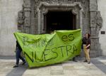 protest. En politibetjent holder vagt uden for en filial af Caja de Madrid/Bankia mens demonstranter går forbi med et banner med påskriften 'Bankia er vores'. 