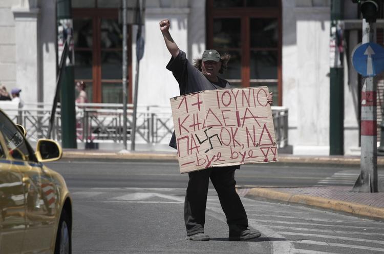 En græsk mand demonstrerer med et skilt med ordene: »17. juni begravelsen af Pasok og Nyt Demokrati«. På søndag skal grækerne vælge landets nye ledere. 
