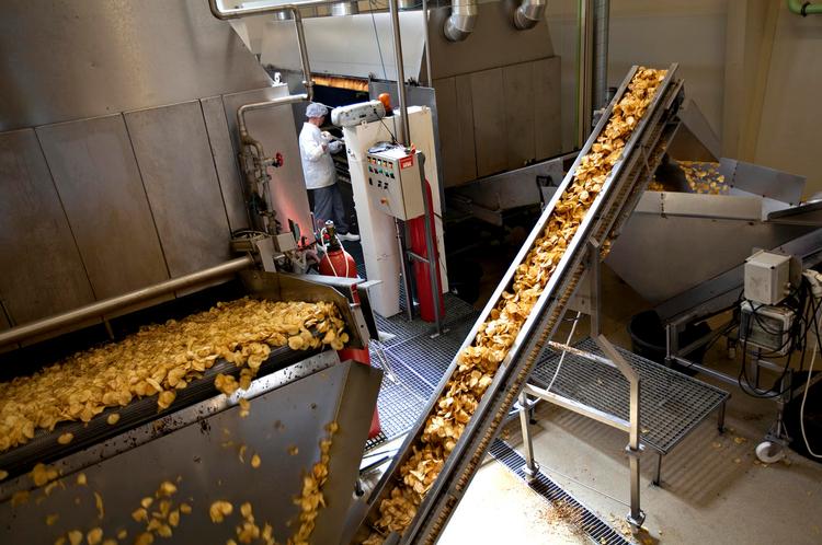 Regn i skiver. Kartofler snittet i 1,5 mm tykke skiver daler fra transportbåndet og ned i 130 grader varm jordnøddeolie. 