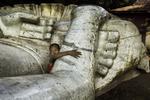En meget lille munk holder om en meget stor Buddha-statue i Mandalay i Burma, 2008. 