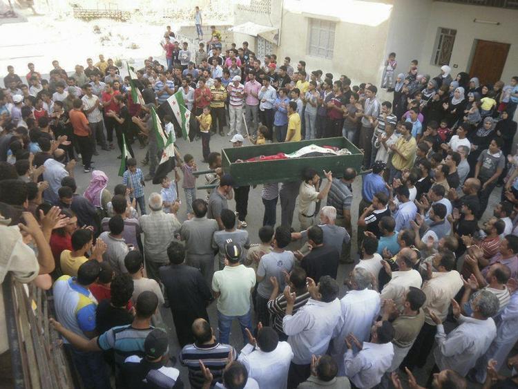 Begravelse. Mennesker forsamles omkring kisten af en ung mand, der er blevet dræbt af syriske regeringsstyrker i byen Daraa. Billedet er taget af en borgerjournalist i Syrien og sendt ud af landet. Det kan være svært at verificere fotos og oplysninger fra Syrien, da pressen ikke kan arbejde frit i landet. 