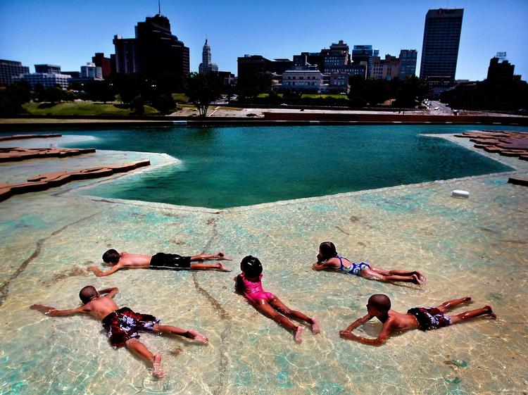 Børn ligger og bliver afkølet i det lave vand i et større bassin i Mud Island River Park i Memphis, Tennessee. 