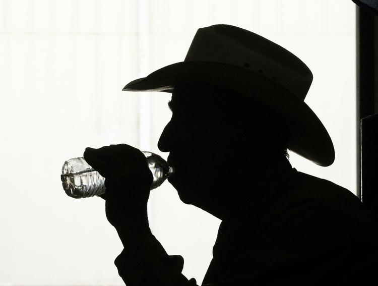 Guy Clark tager en slurk vand, før han bevæger sig ud i varmen i Oklahoma By, Oklahoma. 