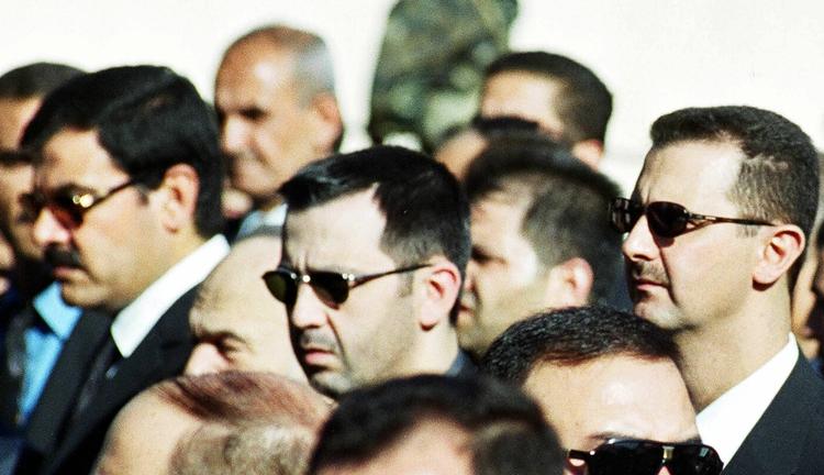 Dræbt. Præsident Assads svoger står på dette billede yderst til venstre - han omkom under bombeangrebet i Damaskus. Præsident Assad selv står yderst til højre. Han har erklæret , at han fortsat vil slå ned på oprøret. 