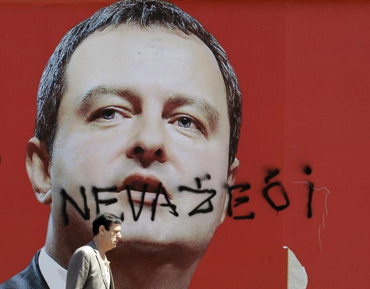 Ugyldig. En mand går forbi en valgplakat af Ivica Dacic. Plakaten er blevet overskrevet med ordet 'ugyldig'. 
