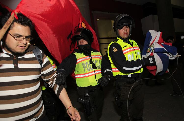 konflikt. En politibetjent fjerner det britiske flag fra demonstranter, der protesterede uden for Storbritanniens ambassade i Ecuadors hovedstad, Quito, i går. 