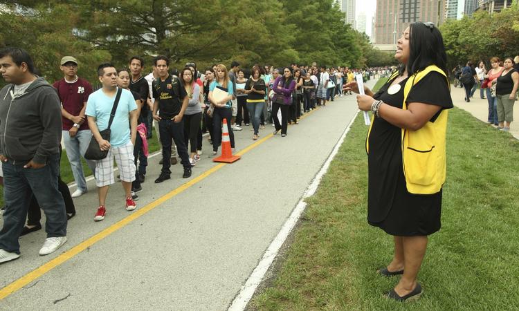 10000. omtrent så mange illegale indvandrere stod i går i kø i Chicago for at komme til kursus i at ansøge om lovligt ophold. En medarbejder forsøger her at dirrigere dem. 