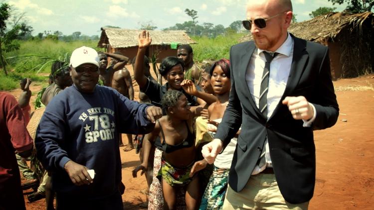 Brügger om 'Ambassadøren': »Jeg ville vise et andet Afrika end NGO'ernes med Bono og børnene med de udspilede maver. Lave en dokumentarfilm om dem, du aldrig ser: Alle dem, der feder den i Afrika, nemlig de tykke hankatte i fedtlaget omkring magten i en fejlslagen afrikansk stat«. 